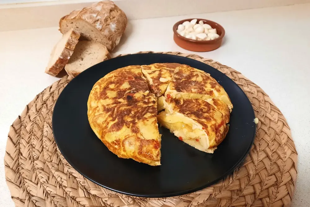 Tortilla de patata casera con ajos en aceite y pimientos del piquillo